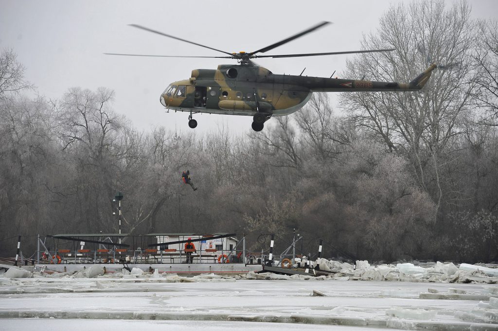 Tiszacsege, 2017. február 13. Honvédségi helikopterrel mentik a levonuló jeges ár által elsodort és a folyó közepén a jégtáblák közé szorult tiszacsegei komp fedélzetérõl az éjjeliõrt 2017. február 13-án. A vízi jármûvön a mentést segítõ munkatárs áll. A szakemberek attól tartanak, hogy egy újabb jégmozgás összeroppantja a kompot. MTI Fotó: Czeglédi Zsolt