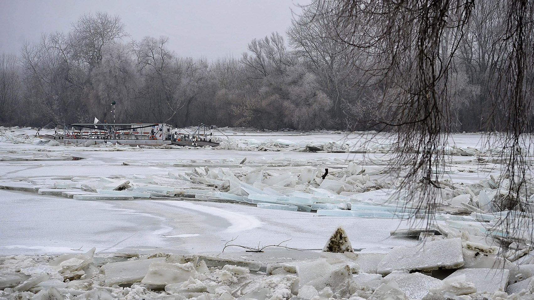 Tiszacsege, 2017. február 13. A levonuló jeges ár által elsodort és a folyó közepén a jégtáblák közé szorult tiszacsegei komp, a fedélzetén az éjjeliőrrel 2017. február 13-án. A szakemberek attól tartanak, hogy egy újabb jégmozgás összeroppantja a járművet, jelenleg helikoptert várnak a helyszínre, hogy azzal megpróbálják kimenteni a kompon tartózkodó férfit. MTI Fotó: Czeglédi Zsolt
